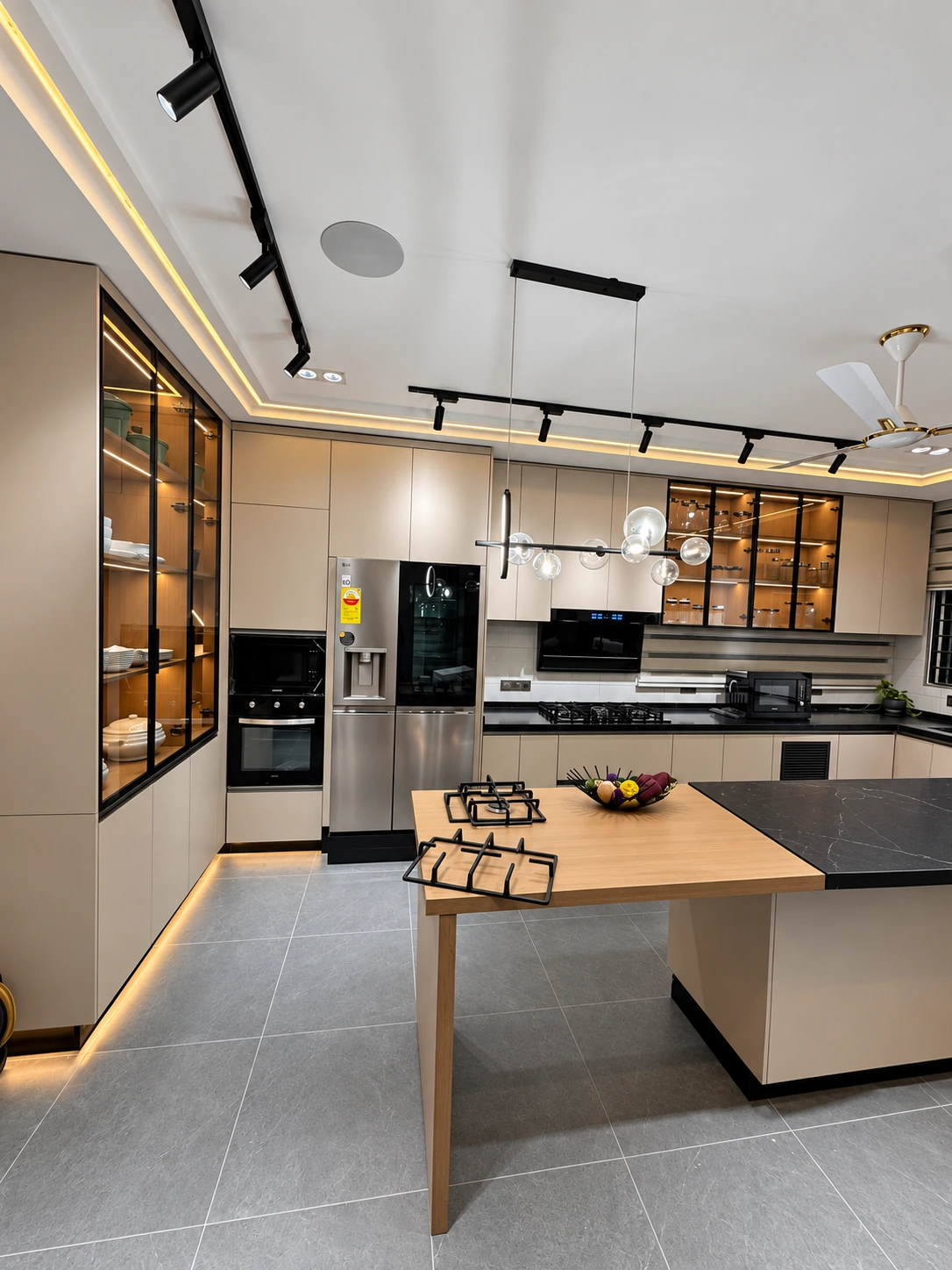 Wider view of the same kitchen showing tall cabinetry, glass-front cupboards and ceiling lighting